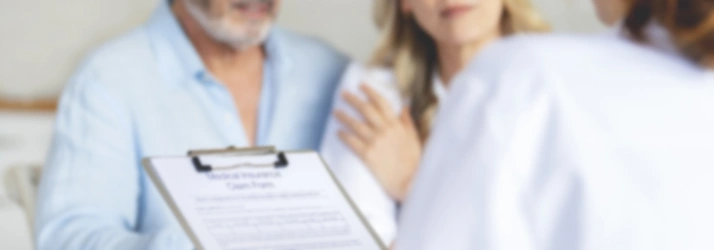 Doctor holding a clipboard with medical forms while speaking with two patients